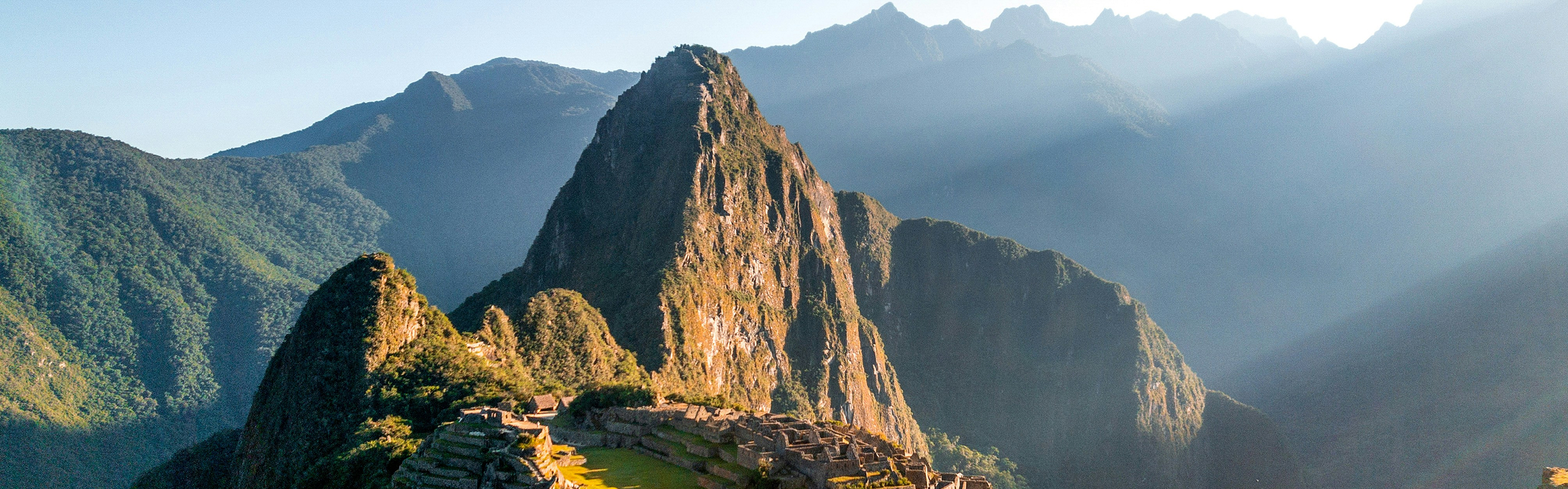 Grüne Berge mit alten Ruinen und Sonnenstrahlen.