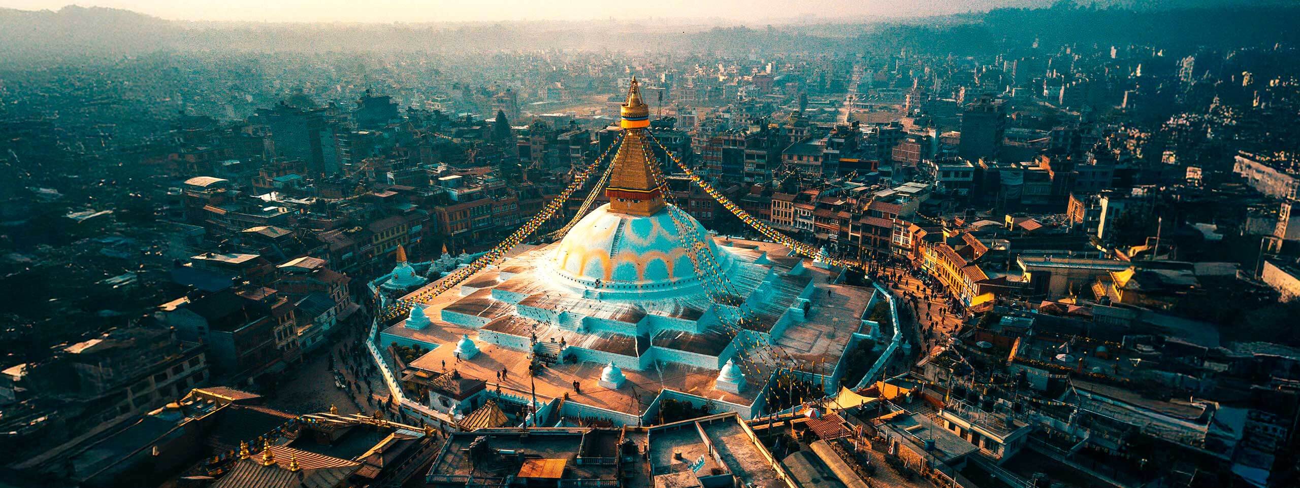 Stupa mit goldenem Turm, umgeben von Stadt im Dunst.