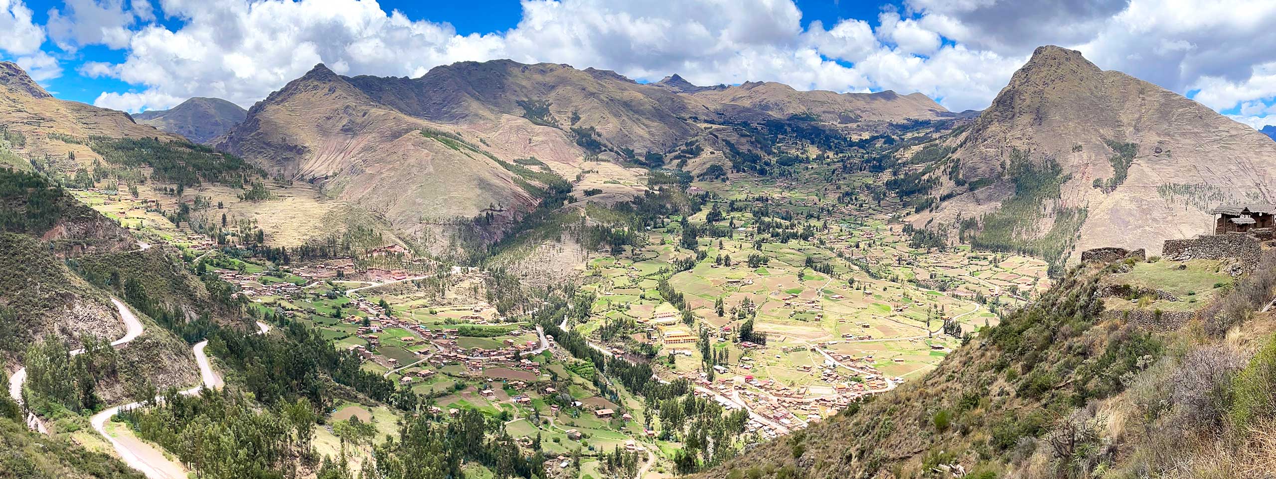 Grünes Gebirgstal mit Dörfern, Feldern und Bergen.