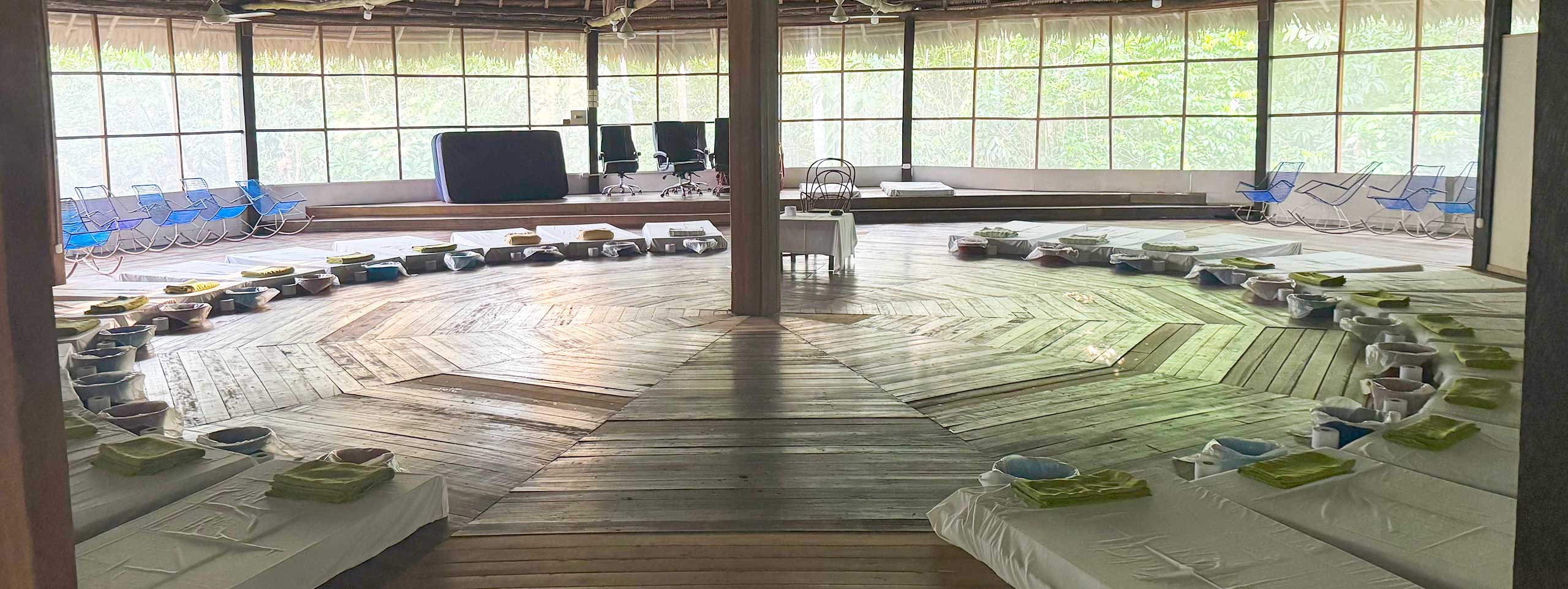 Raum: Matratzen, Schalen, Tücher auf radialem Holzfußboden.