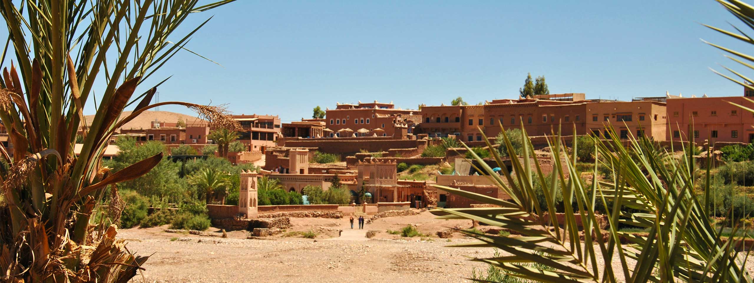 Lehmdorf mit Palmen in trockener Landschaft.