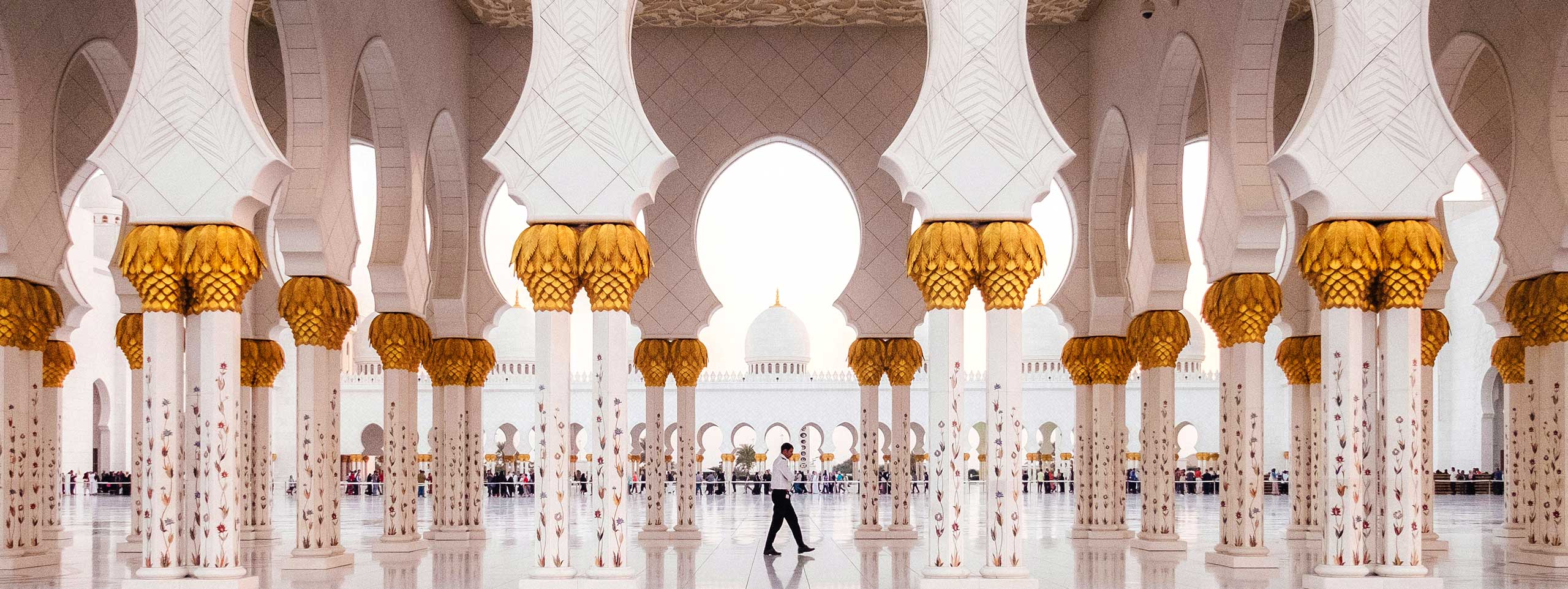 Weißer Säulengang mit goldenen Kapitellen; eine Person.
