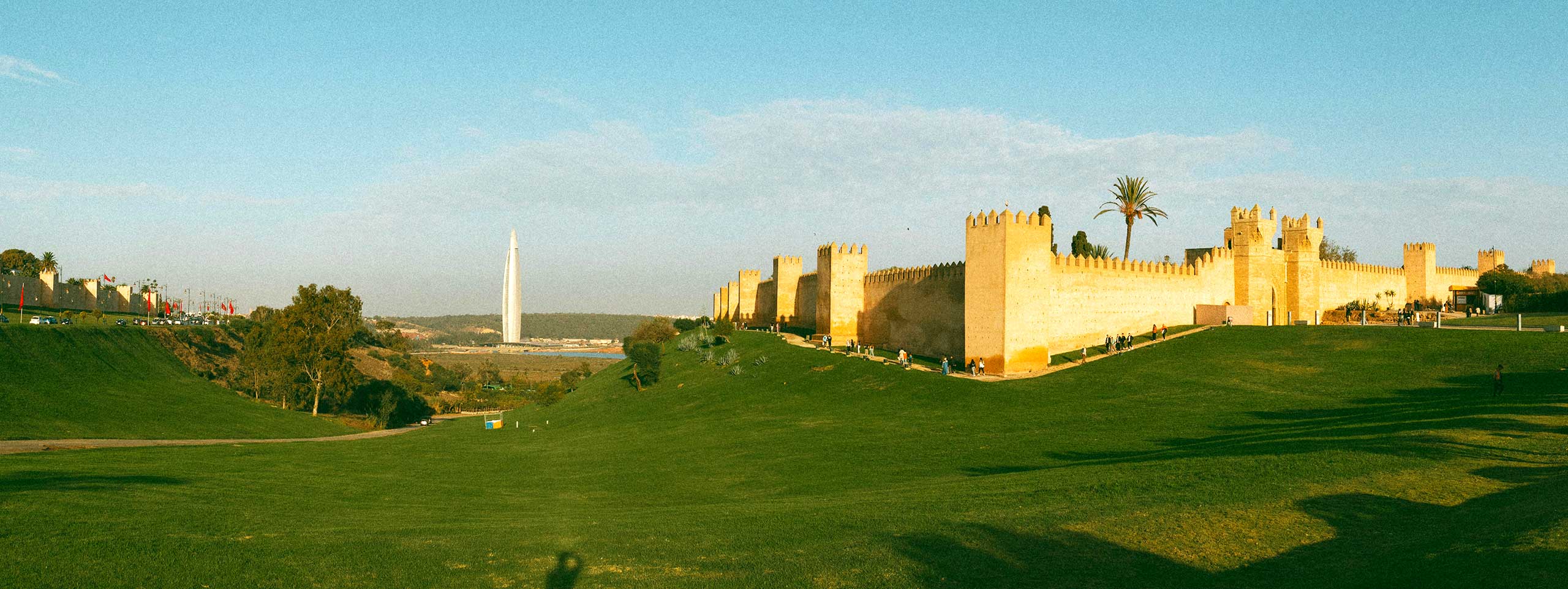 Grüne Hügel, alte Festungsmauer, hoher weißer Turm.
